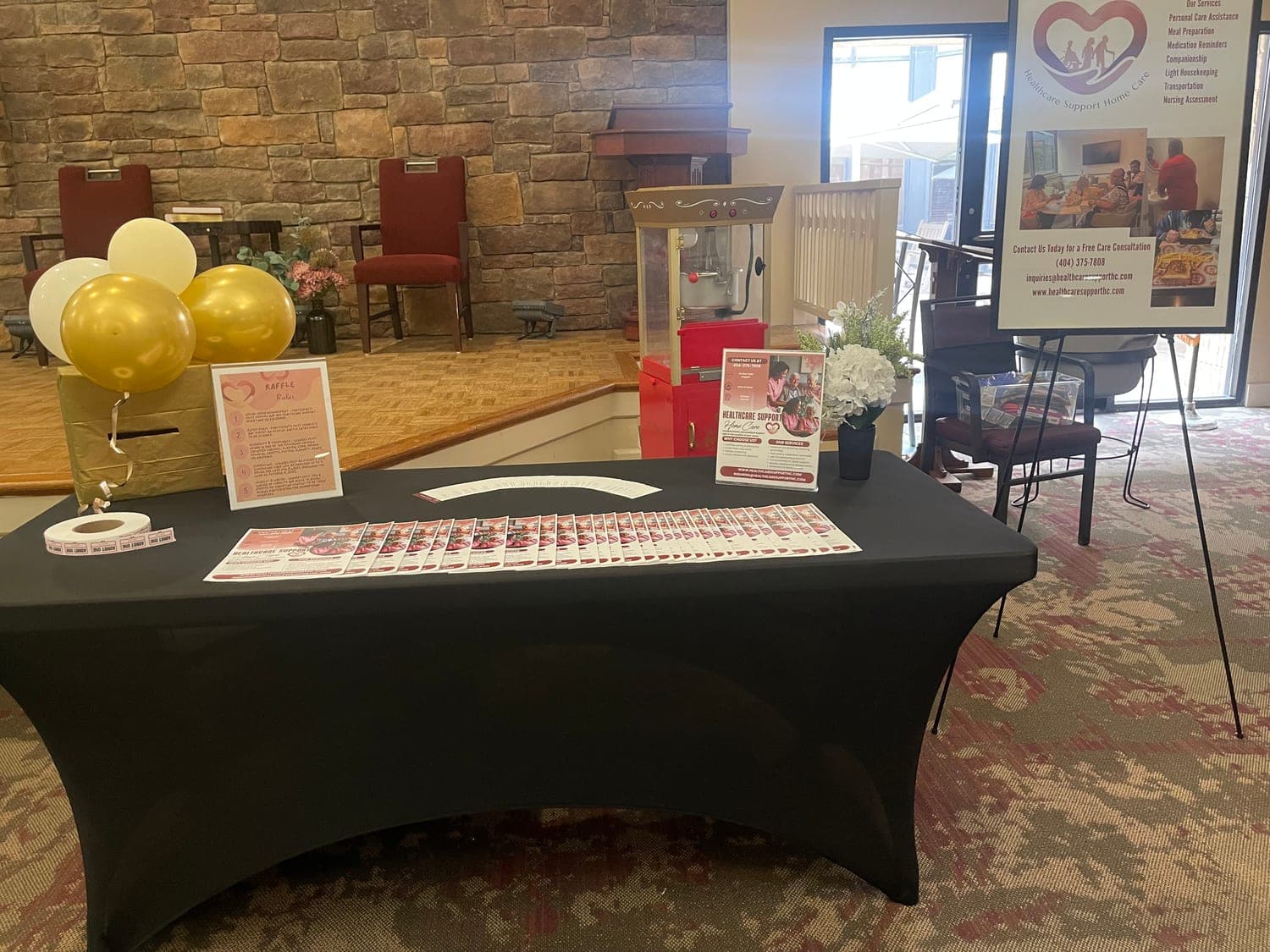 The Healthcare Support table set up with flyers, a popcorn machine and balloons at Pruitt Christian City