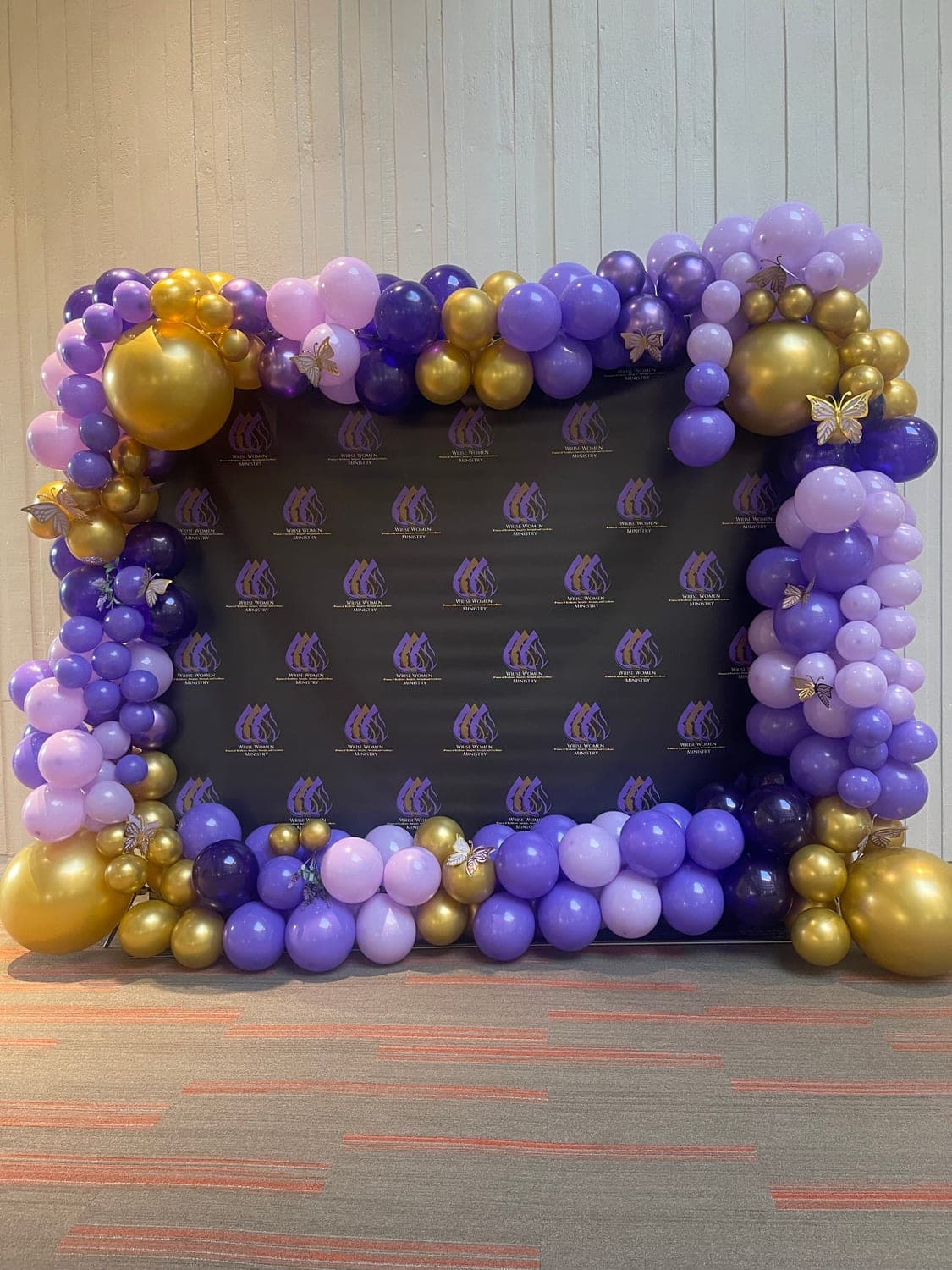 A purple and gold balloon wall around the photo backdrop at the WRISE Women's Conference 2025, hosted by Rise Again Ministries in Buckhead, Atlanta